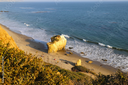 a shot of the deep blue ocean and the waves rolling into the beach with people relaxing on the beachat El Matador beach in Malibu California photo