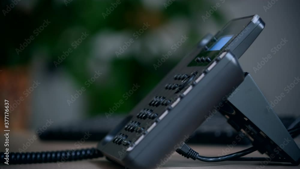 Office worker uses a landline phone to answer incoming calls and dialing a number to make a call. Businesswoman picking up the phone to answer a phone call. Close-up of women's hands with a phone