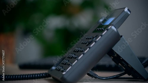 Office worker uses a landline phone to answer incoming calls and dialing a number to make a call. Businesswoman picking up the phone to answer a phone call. Close-up of women's hands with a phone photo