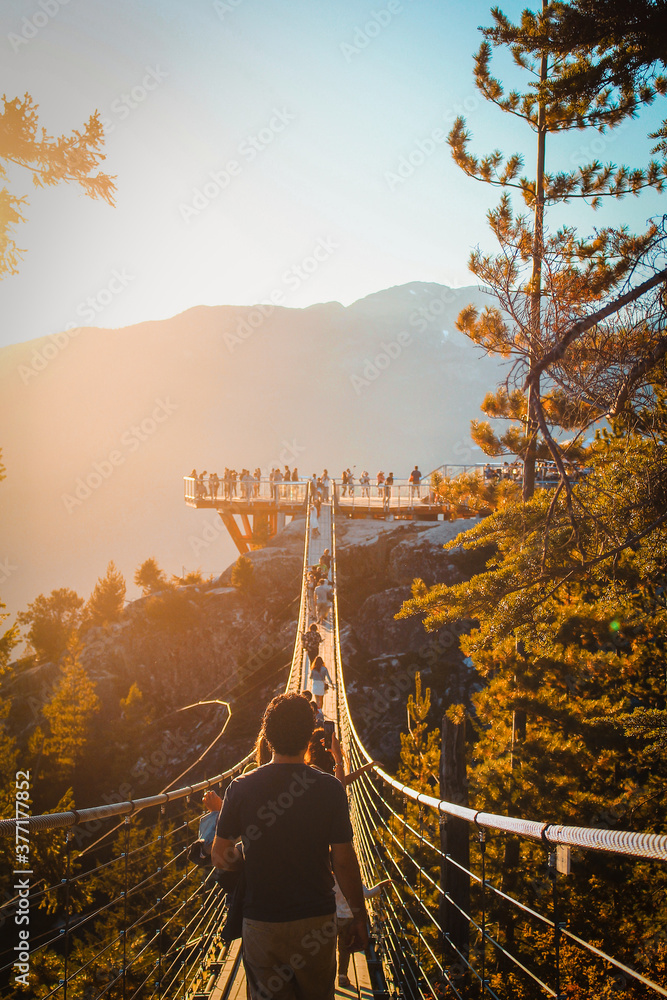 Fototapeta premium People walk along a suspension bridge during sunset