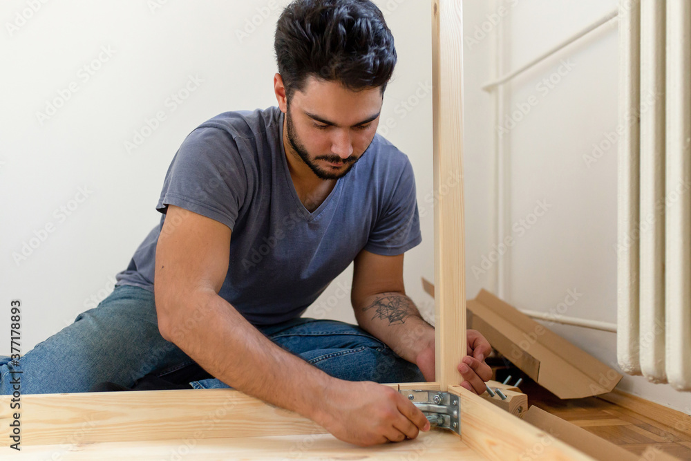 Young man assembling a furniture Young man assembling a furniture