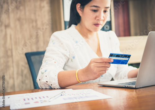 Happy asian woman doing online shopping at home. Asia women holding a credit card and purchasing online with laptop computer. digital technology communication internet of things concept.