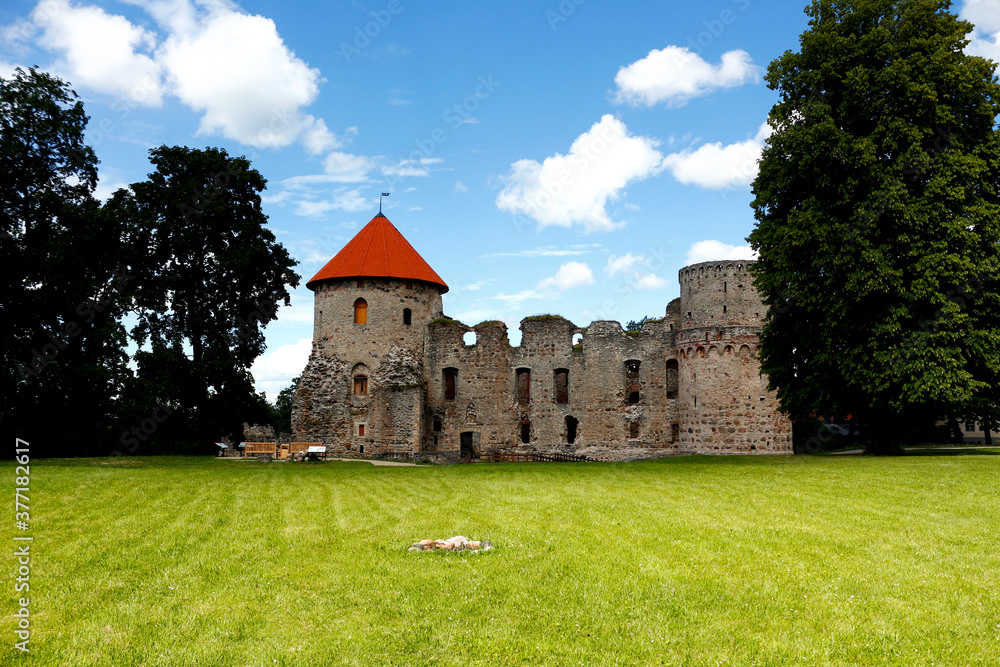Nice view of the old castle in the city of Cesis, Latvia. A colorful landscape with a medieval fortress and a tower with a red roof.