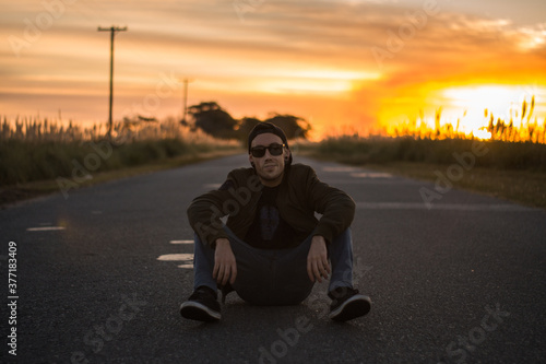 young man on the road with sunset sun on his back, travel concept, trust friends campaign, social media, man advertising