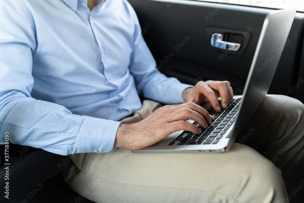Young businessman sitting in taxi and using laptop Young businessman sitting in taxi and using laptop