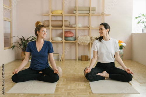 Two adult women practice yoga in a yoga studio photo