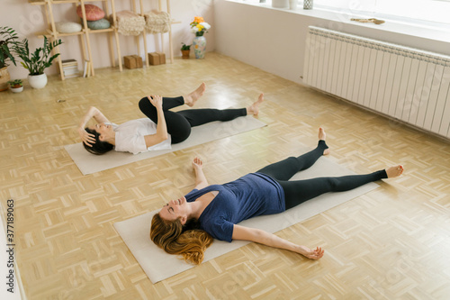 Two adult women practice yoga in a yoga studio photo