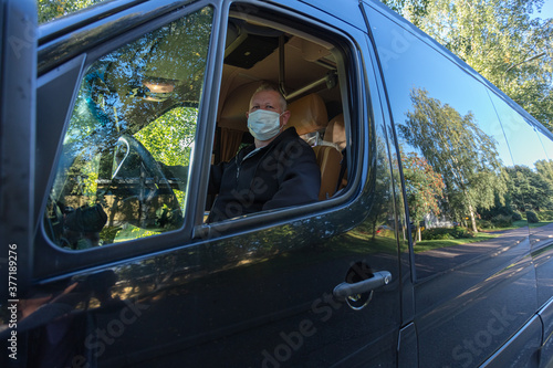 The driver in the medical mask is driving the bus Safe driving during a pandemic, protection against coronavirus