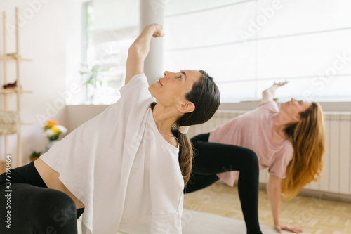 Two adult women practice yoga in a yoga studio photo