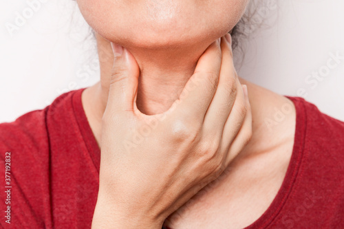 The woman is holding her throat with her hand. The woman's throat hurts.