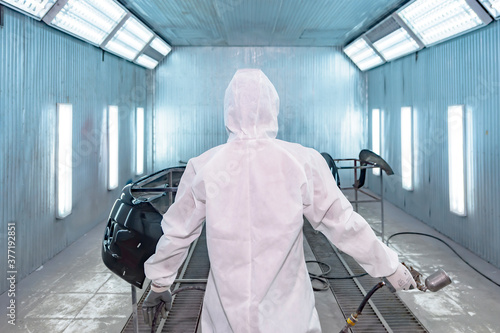 Foto automobile repairman painter in protective workwear and respirator painting car