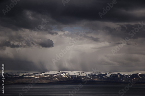 Amazing flowing rainy clouds in evening mountains. Dramatic rainy clouds above the mountain. Beautiful nature of Iceland. Landscape photography.