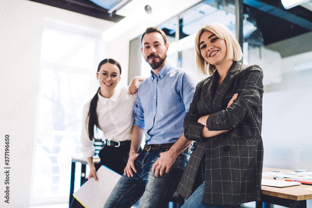 Happy coworkers smiling and standing at desk and in office Happy coworkers smiling and standing at desk and in office