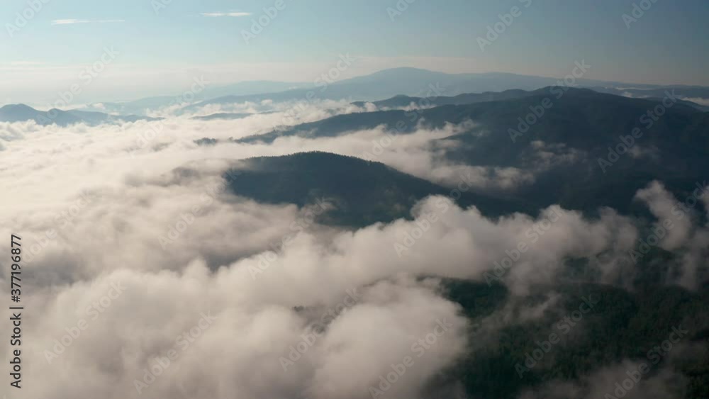 Drone flight over low clouds and morning mists covered mountain slopes at sunrise, the Rhodope Mountains in Bulgaria Drone flight over low clouds and morning mists covered mountain slopes at sunrise, the Rhodope Mountains in Bulgaria
