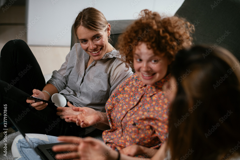 Girlfriends talking and laughing in office. Beautiful women drinking coffee in the office.. Girlfriends talking and laughing in office. Beautiful women drinking coffee in the office..