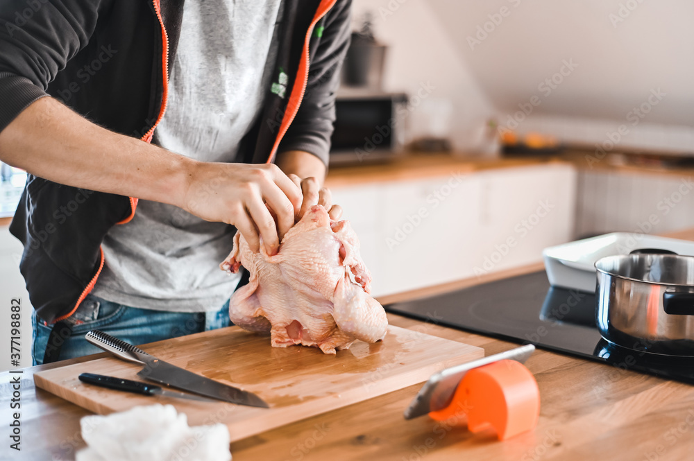 attractive nerd guy with glasses in stylish kitchen follows a recipe on the phone prepares chicken