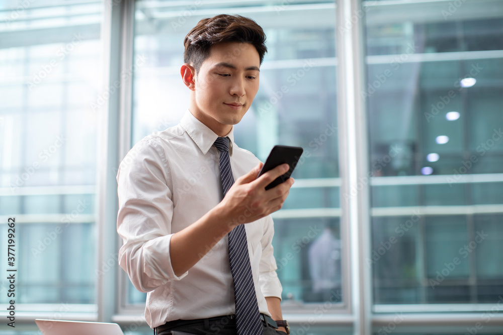Confident businessman using smartphone in office Confident businessman using smartphone in office