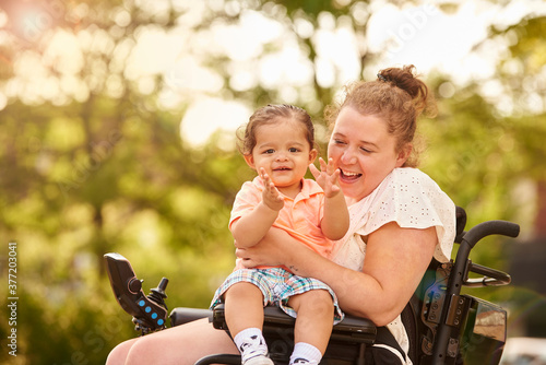 Young child sitting on disabled mother's lap.