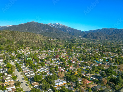 stunning aerial shot of the snow capped mountain ranges and blue skies of Monrovia California with a view of the homes below surrounded by lush green trees photo