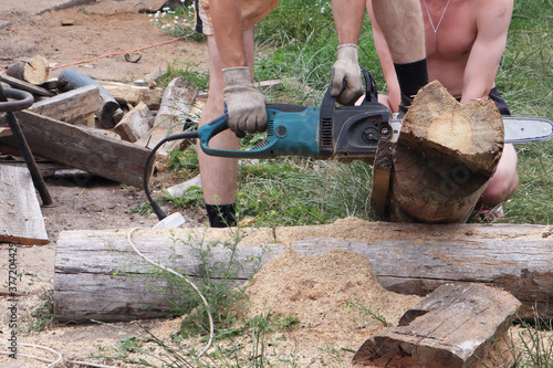 A man saws wood with a saw outside on a summer day. Work concept.