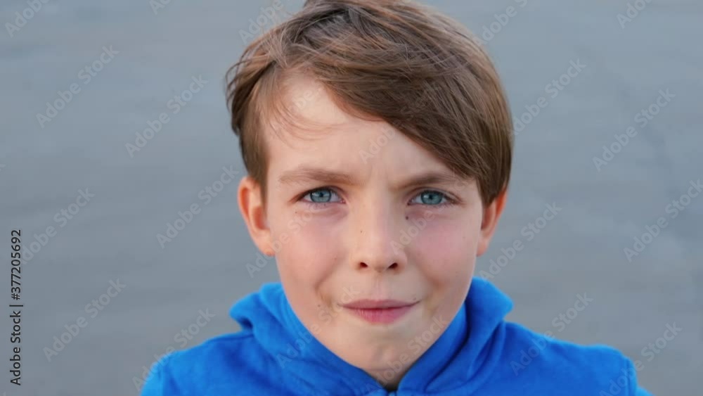 Portrait of boy looking into the camera. A teenager is chewing gum. Hair movement in the wind. Positive balance of the child's psyche. Portrait of boy looking into the camera. A teenager is chewing gum. Hair movement in the wind. Positive balance of the child's psyche.