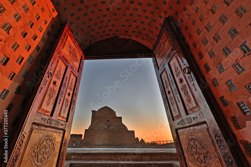 Ancient mausoleum through wooden doors in the historical Mizdakhan cemetery at the sunset, in Nukus, Uzbekistan. photo