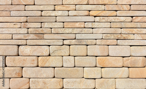 The wall is lined with hewn rounded yellow sandstone stone.