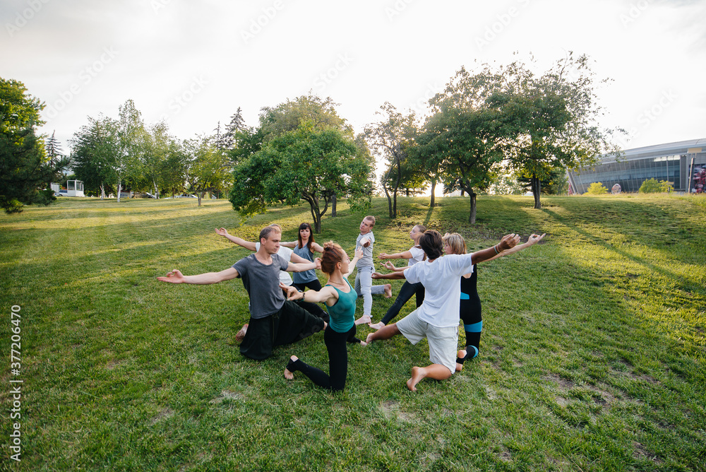 Obraz premium A group of people do yoga in a circle in the open air during sunset. Healthy lifestyle, meditation and Wellness