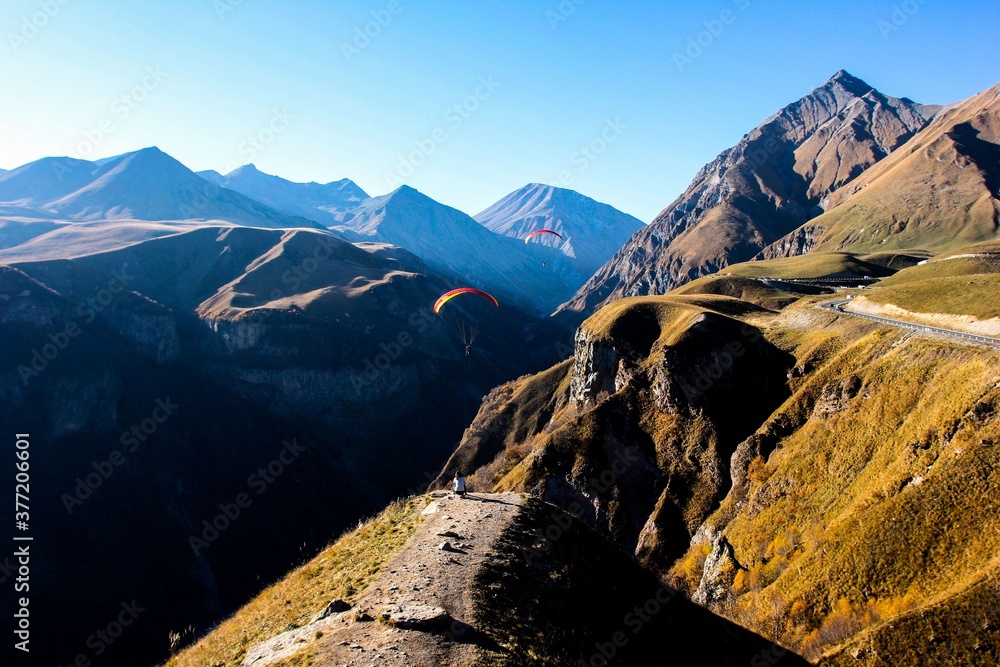 people fly on paragliders over a gorge in the mountains