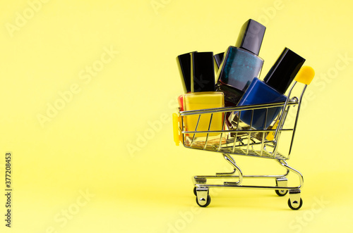 Different colors of nail polishes in a shopping trolley on a yellow background. beauty and fashion trendy concept. flat lay, top view