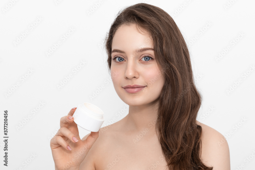 A woman with blue eyes and long hair holds a white cream container, isolated on a white background. A woman with blue eyes and long hair holds a white cream container, isolated on a white background.