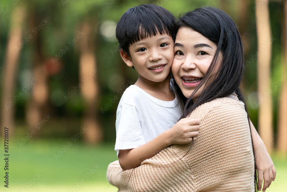 Portrait beautiful mother and child happily hugged in park. Asian family mom and child are hugging and looking at the camera, cute and warm. Portrait beautiful mother and child happily hugged in park. Asian family mom and child are hugging and looking at the camera, cute and warm.