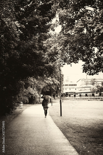 Woman with umbrella walking through a park.