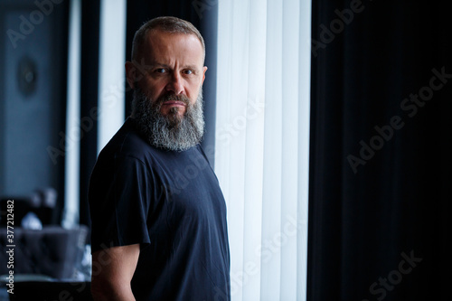 Portrait of a gray-haired adult successful man with a serious face in a black t-shirt