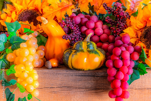 Sunflowers  grapes  and squash  fill a decorated Thanksgiving mantel in the morning light.