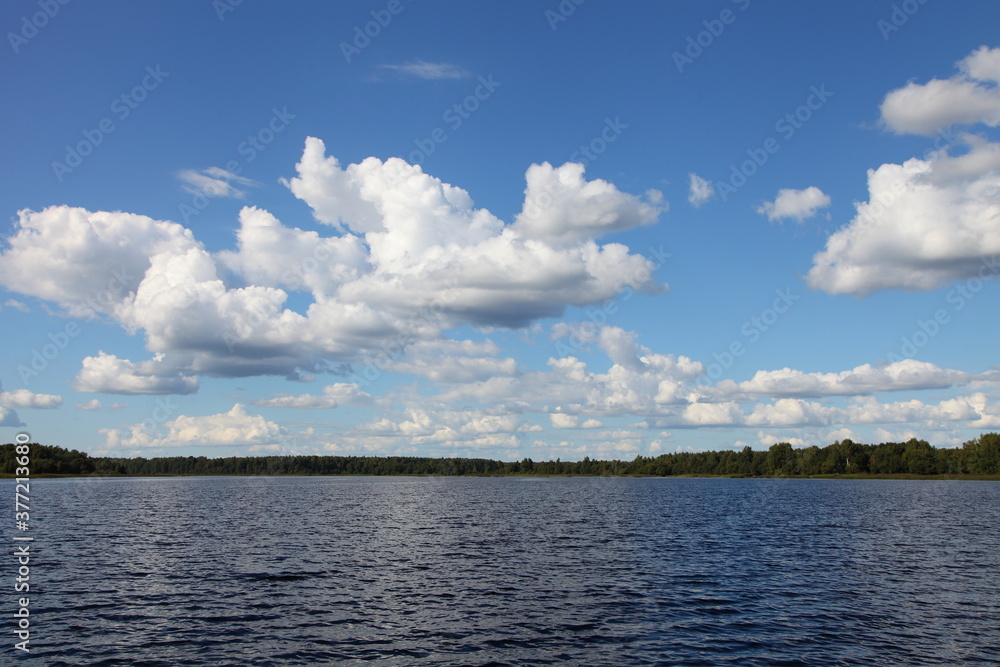 Russisn riverscape view beautiful river water, green forest strip on horizon and blue sky with white clouds at summer day, nature river landscape, ecological outdoor active boating tourism recreation