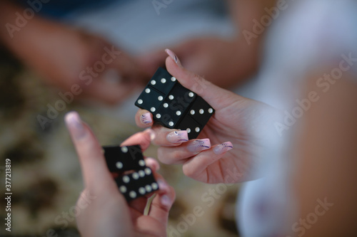 Hands of a girl with black dominoes in a woman's hand, close-up