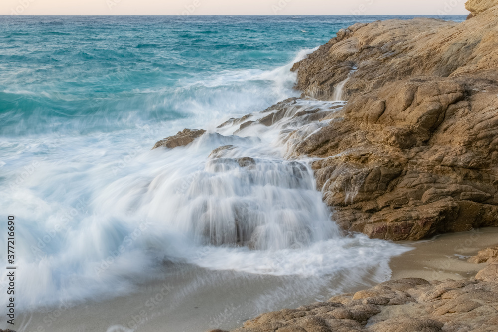 Long exposure time image shore in beach with water flowing from the stones in Ikaria, Island in the Aegean Sea, Greece