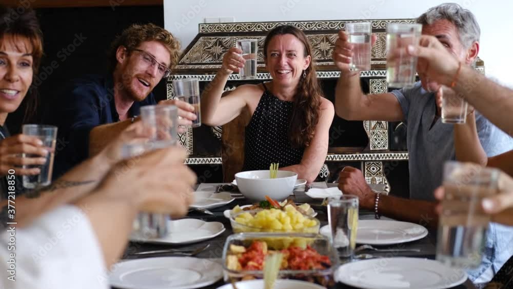 Diverse group of multiethnic friends toasting with glasses and enjoying meal in outdoor cafe or home. Leisure, food and drinks, people and holidays concept Diverse group of multiethnic friends toasting with glasses and enjoying meal in outdoor cafe or home. Leisure, food and drinks, people and holidays concept