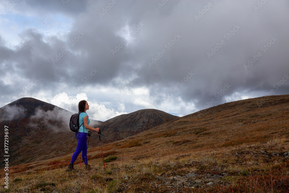 Adventurous Girl Hiking up the Nares Mountain during a cloudy and sunny evening. Taken at Carcross, near Whitehorse, Yukon, Canada.