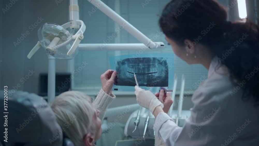 professional dentist female show panoramic mouth xray image to patient