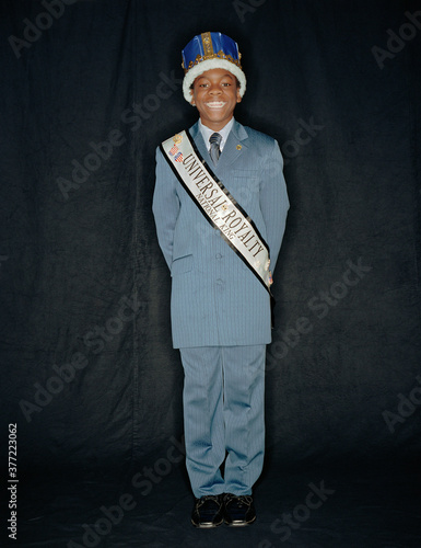 African boy wearing crown and pageant sash