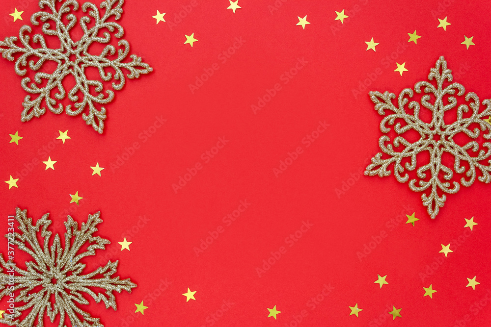 Christmas frame made of gold snowflakes and starry confetti on red background. Place for your text. Selective focus. Christmas frame made of gold snowflakes and starry confetti on red background. Place for your text. Selective focus.