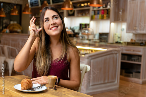 Young woman drinking coffee  making the sign of listening.