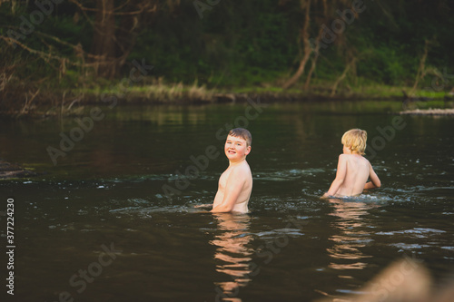 Fototapeta Naklejka Na Ścianę i Meble -  Two brothers swimming in river with strong current. Smiling while splashing in water.