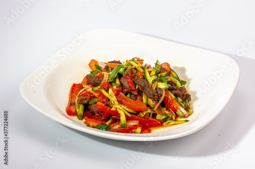 Salad of fried vegetables and beef with tomatoes and onions is on the plate