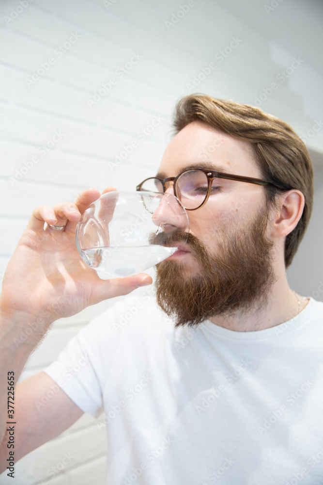 Young bearded man drinking water from a glass. Healthy lifestyle concept. Young bearded man drinking water from a glass. Healthy lifestyle concept.