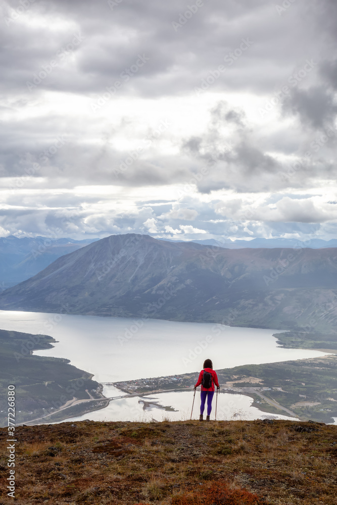 Adventurous Girl Hiking up the Nares Mountain during a cloudy and sunny evening. Taken at Carcross, near Whitehorse, Yukon, Canada.
