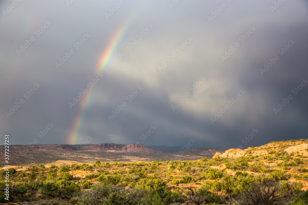A rainbow forming behind the rock formations of Arches National Park after a thunderstorm. A rainbow forming behind the rock formations of Arches National Park after a thunderstorm.