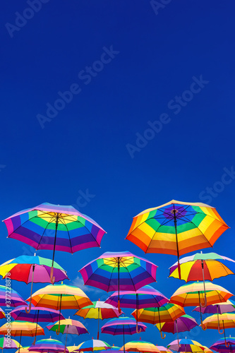 Rainbow Colored Umbrellas Levitating On The Background Of A Blue Sky